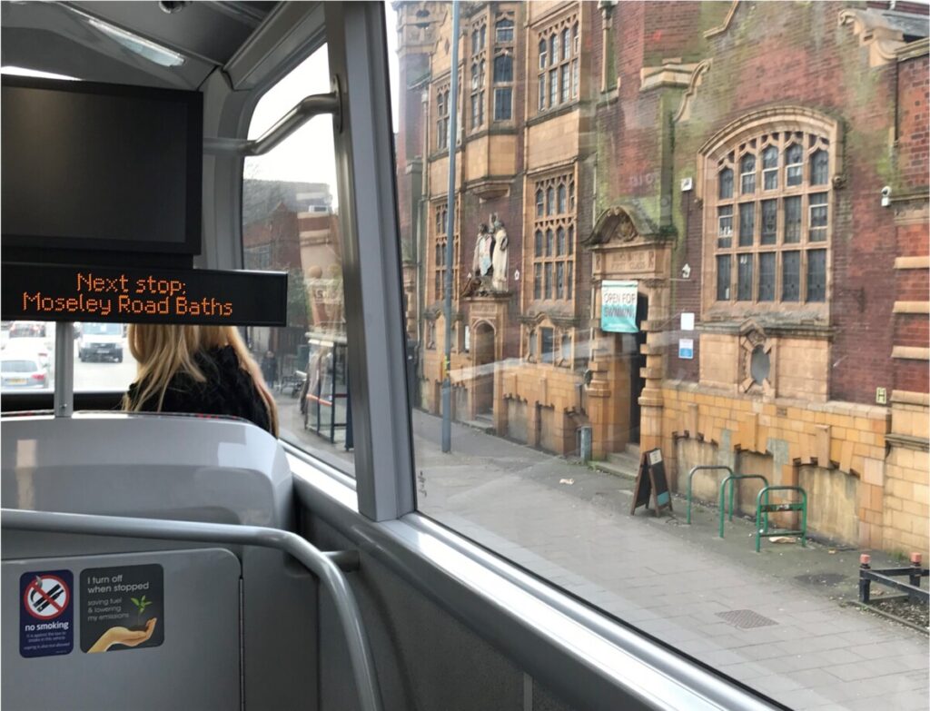 A picture of Moseley Road Baths taken from the number 50 bus. This electronic display on the bus says: Next stop Moseley Road Baths